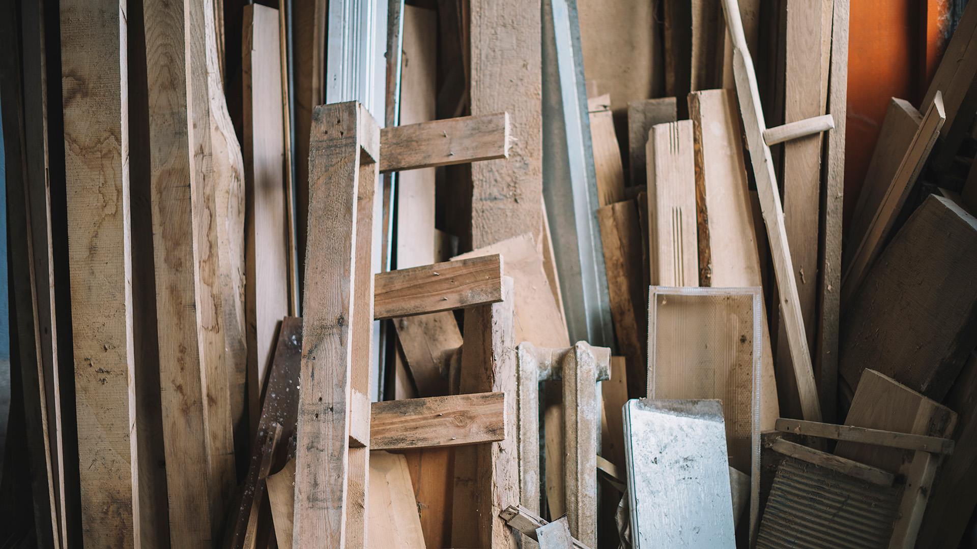 Trämaterial staplade mot en vägg.